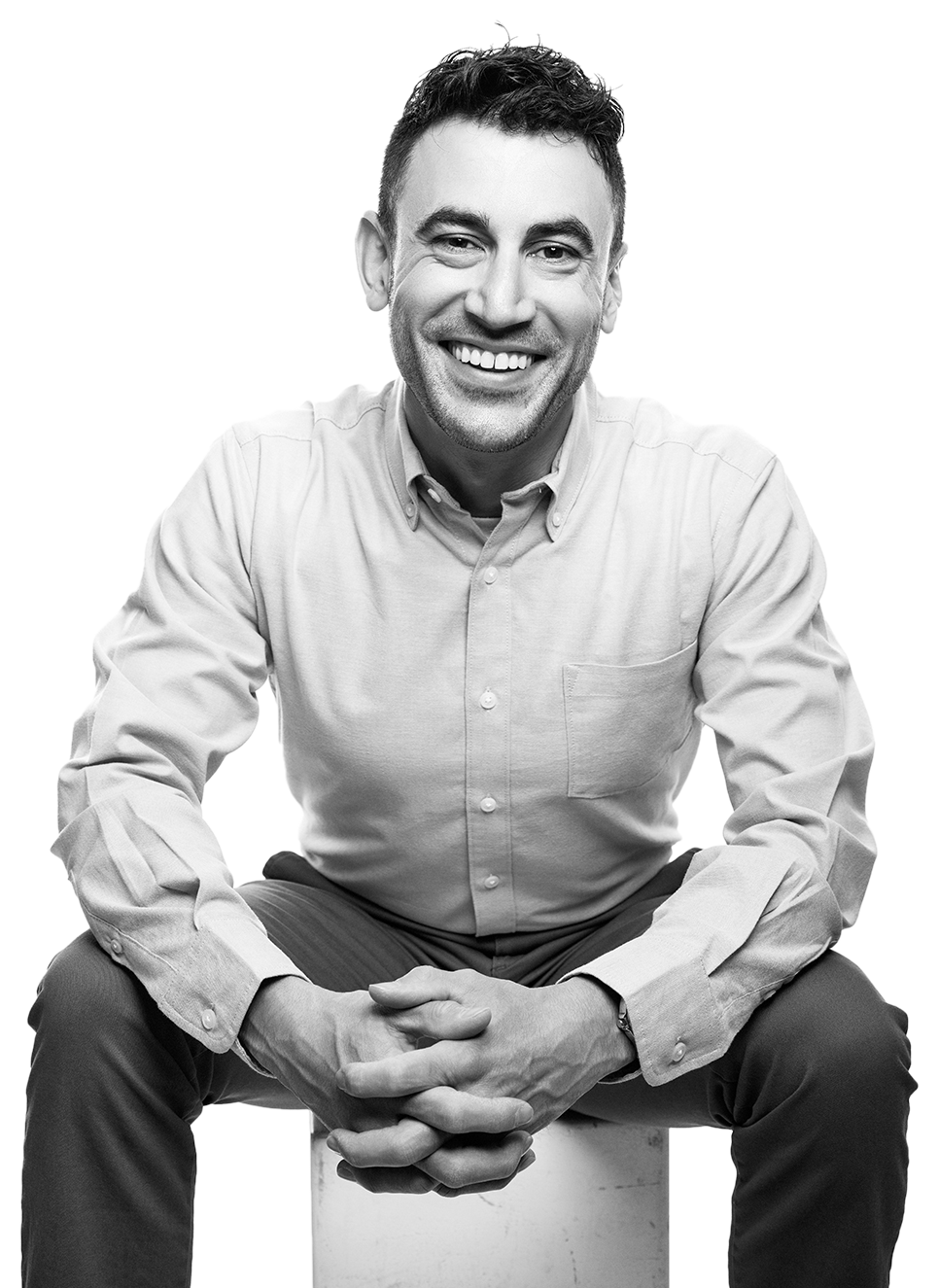 Sal Tringali seated on a stool, smiling, black and white portrait